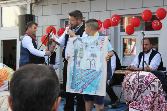 Kirsten Kötter: Ender Cetin shows my painting during a special event. A boy holds my painting (photography 2014-06-22)